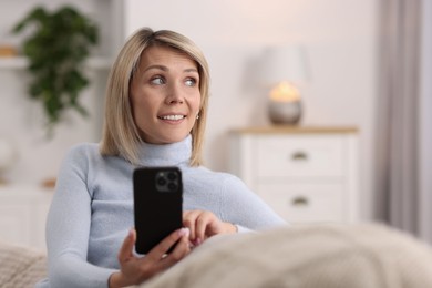 Happy woman using mobile phone at home, space for text