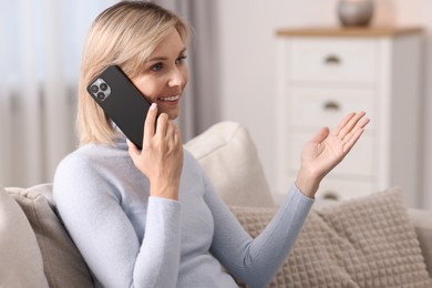 Photo of Happy woman talking on phone at home