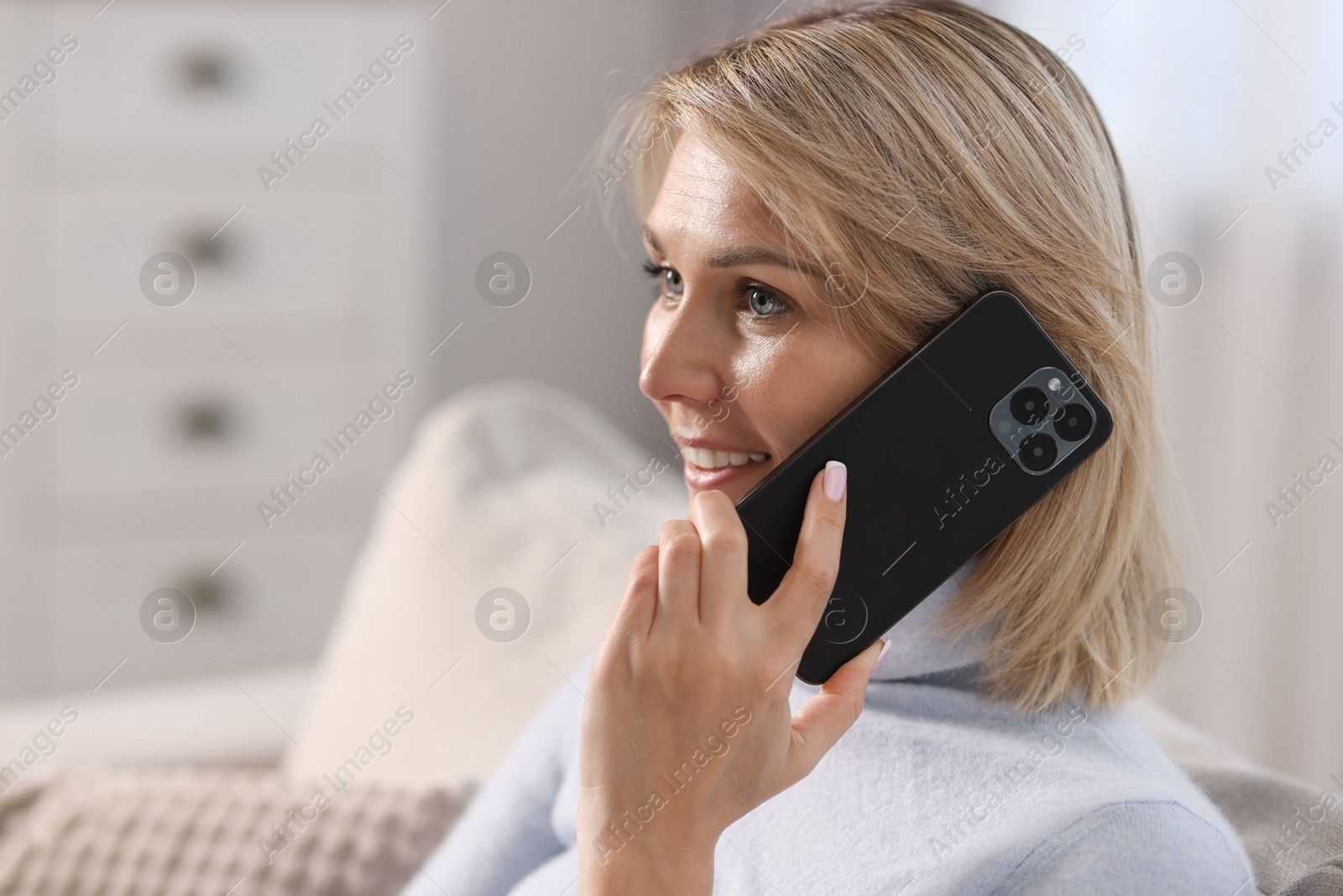 Photo of Happy woman talking on phone at home, space for text
