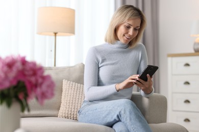 Happy woman using mobile phone at home