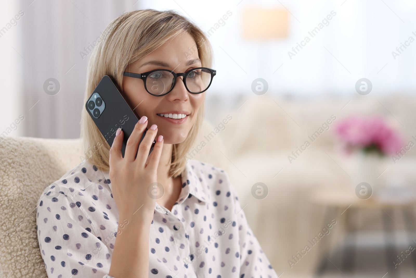 Photo of Happy woman talking on phone at home, space for text