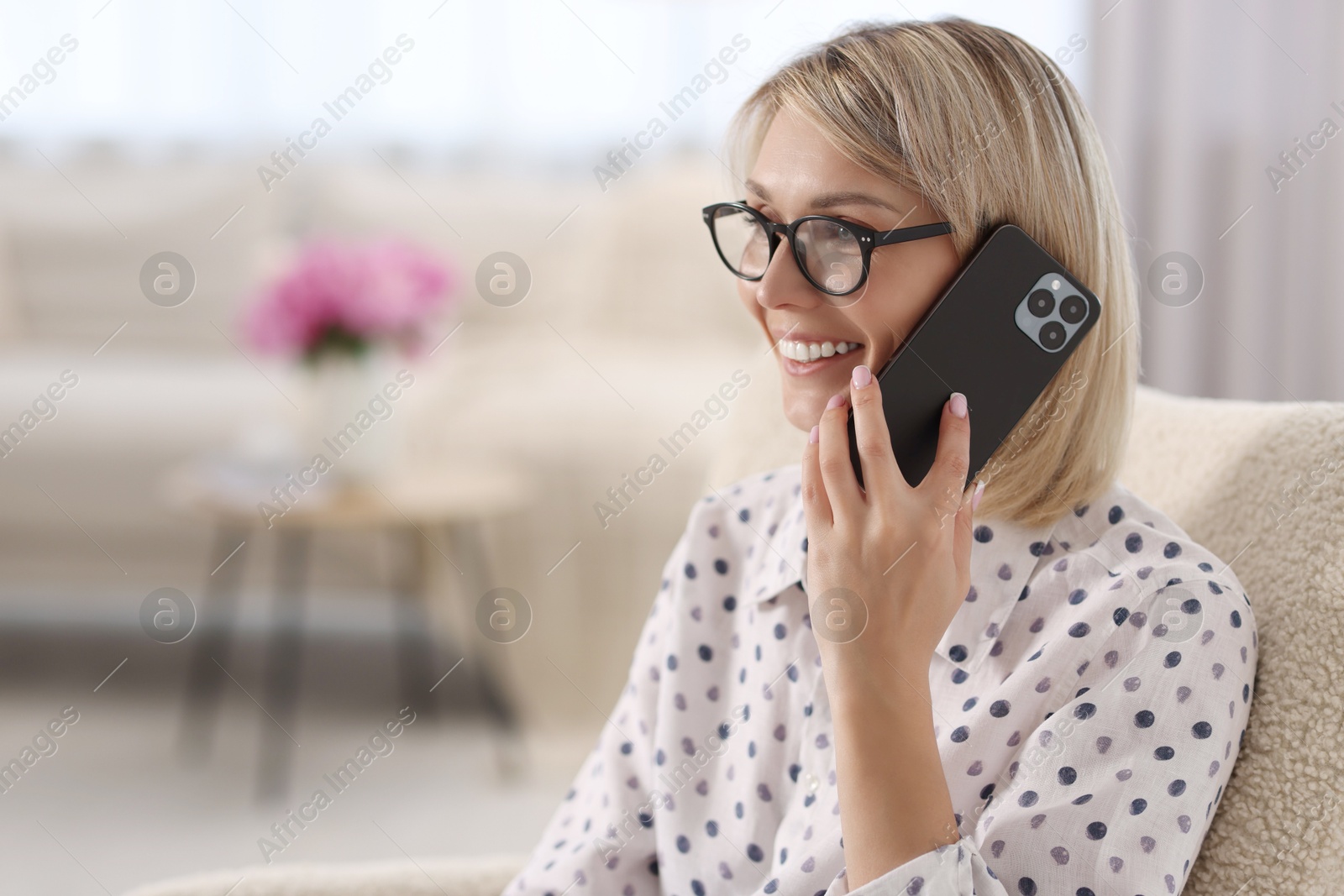 Photo of Happy woman talking on phone at home, space for text