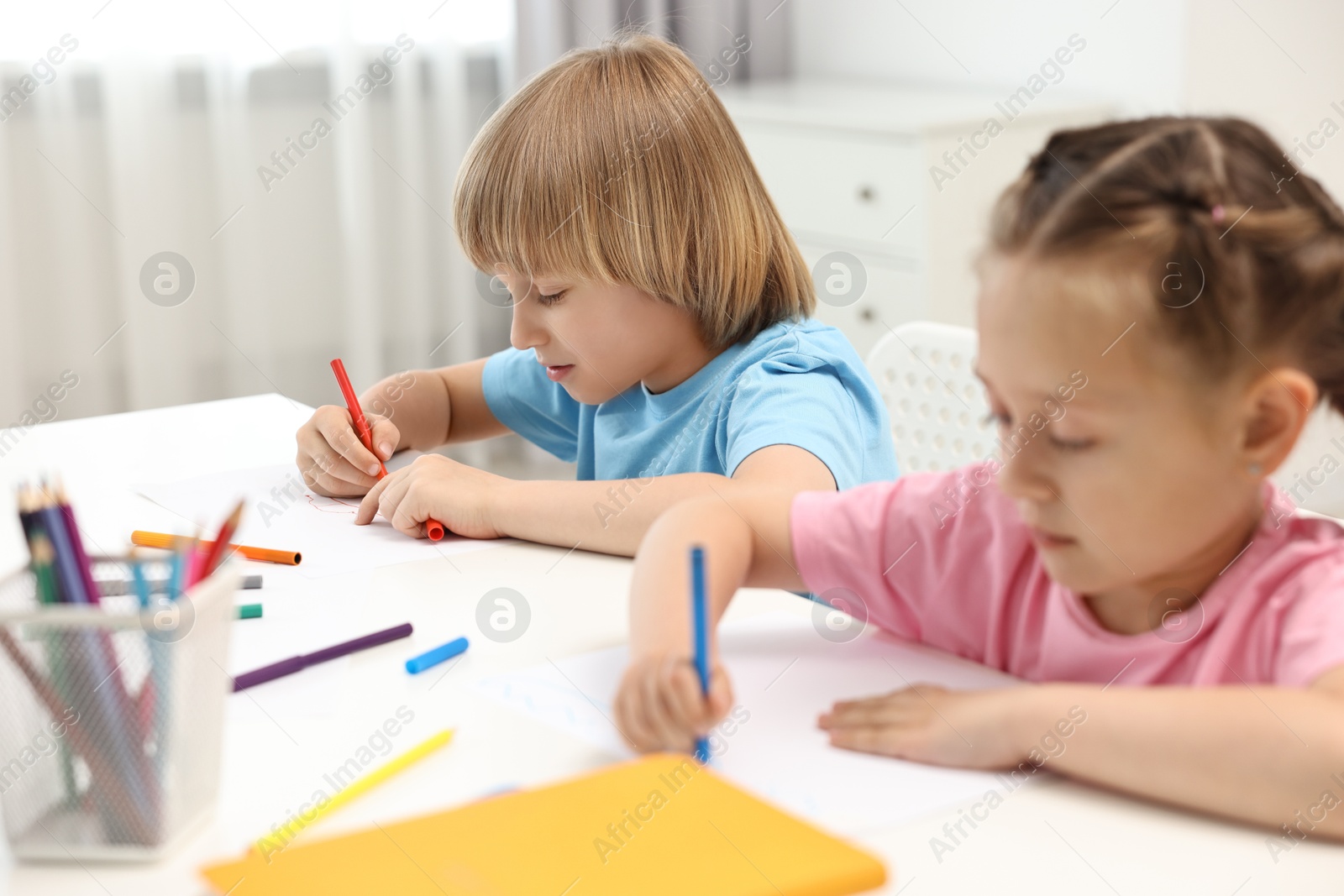 Photo of Cute little children drawing at table indoors