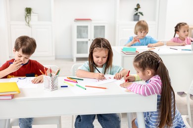 Photo of Group of children drawing at table indoors