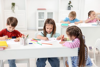 Photo of Group of children drawing at table indoors