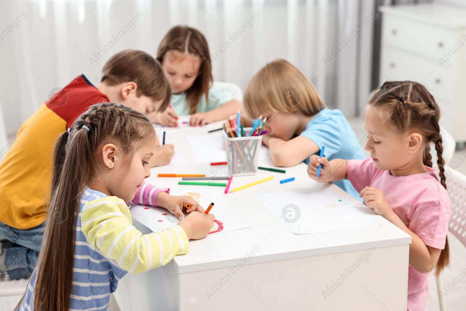 Photo of Group of children drawing at table indoors