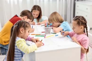 Photo of Group of children drawing at table indoors