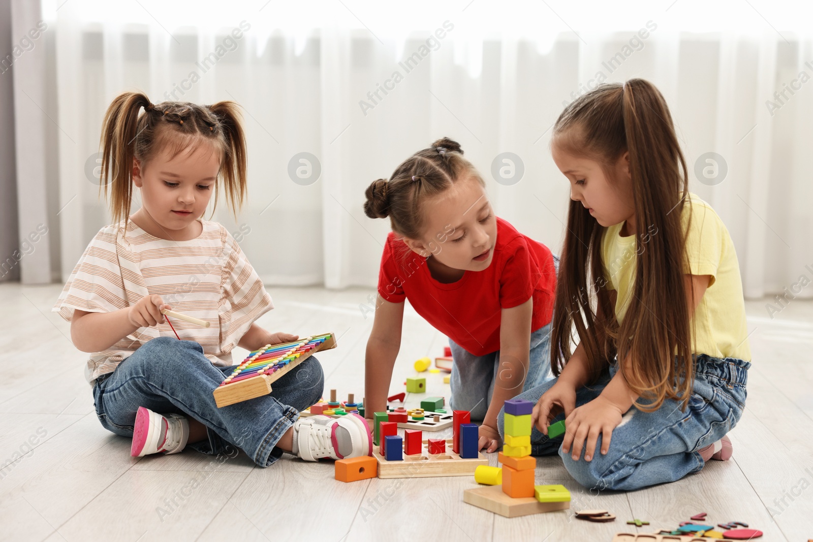 Photo of Cute little children playing together on floor indoors