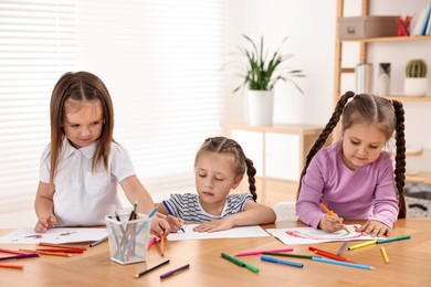 Photo of Cute little children drawing at wooden table indoors