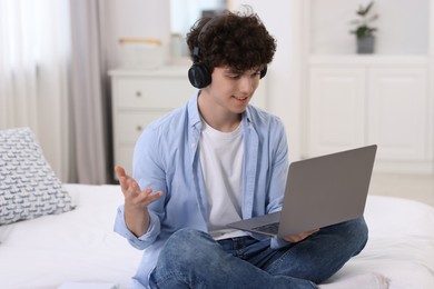 Teenager in headphones having video chat via laptop at home. Remote work