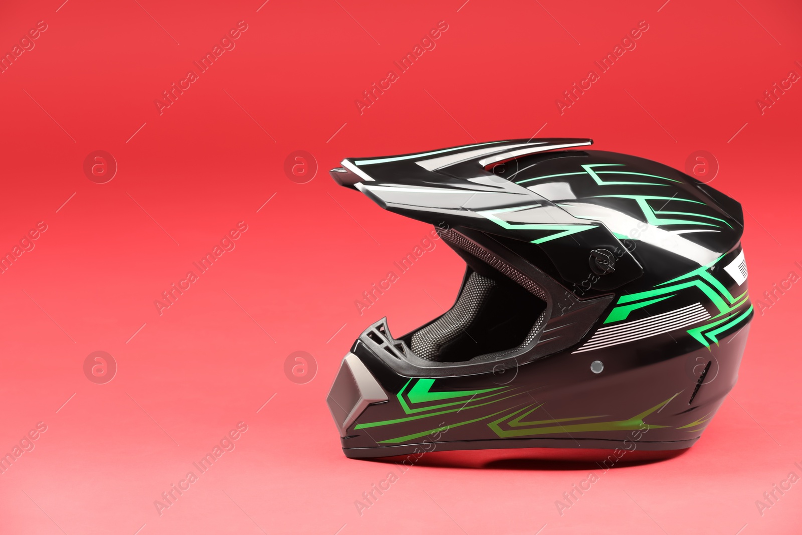 Photo of Modern motorcycle helmet with visor on red background. Space for text
