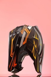 Modern motorcycle helmet with visor on mirror surface against pink background