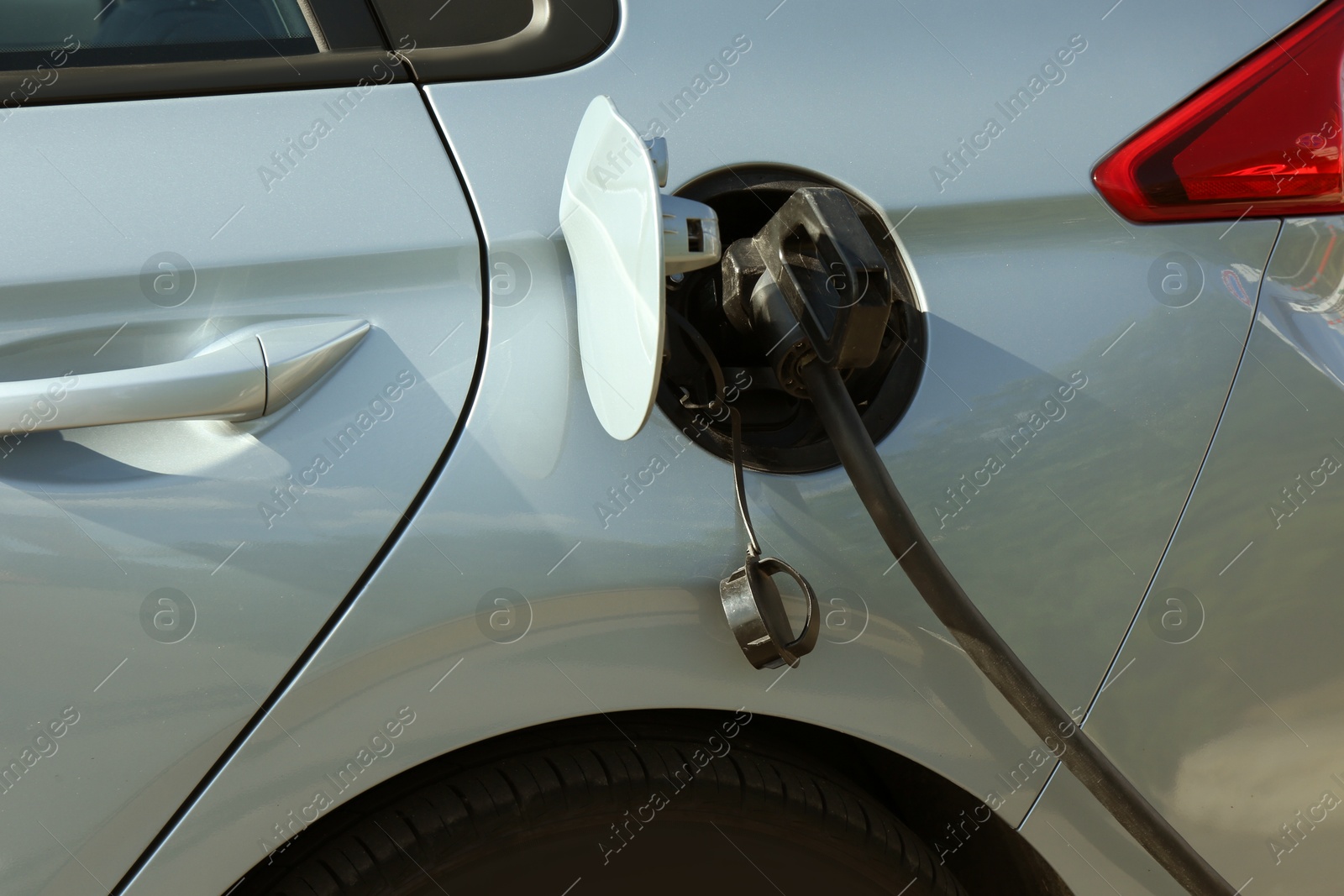 Photo of Charging modern electric car from station outdoors