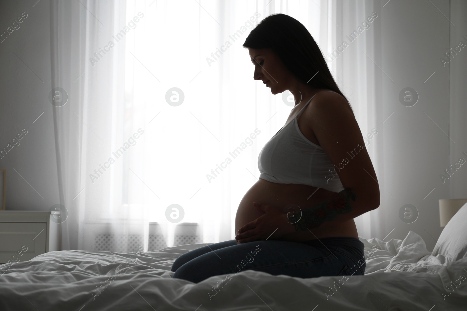 Photo of Beautiful pregnant woman on bed at home