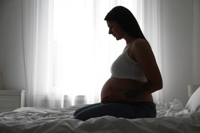 Beautiful pregnant woman on bed at home