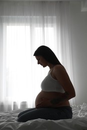 Photo of Beautiful pregnant woman on bed at home