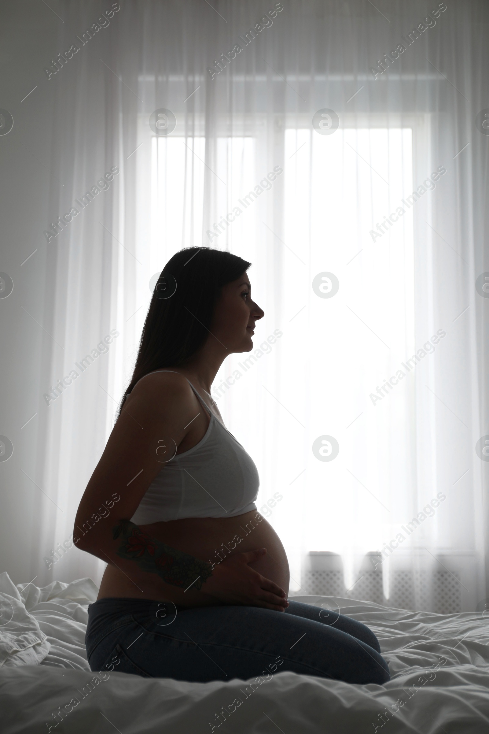 Photo of Beautiful pregnant woman on bed at home