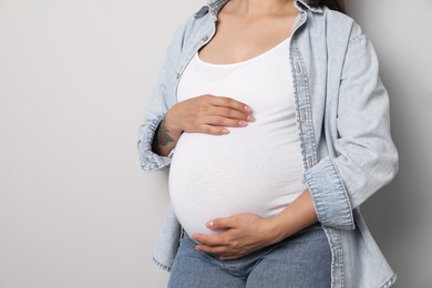 Pregnant woman on gray background, closeup. Space for text