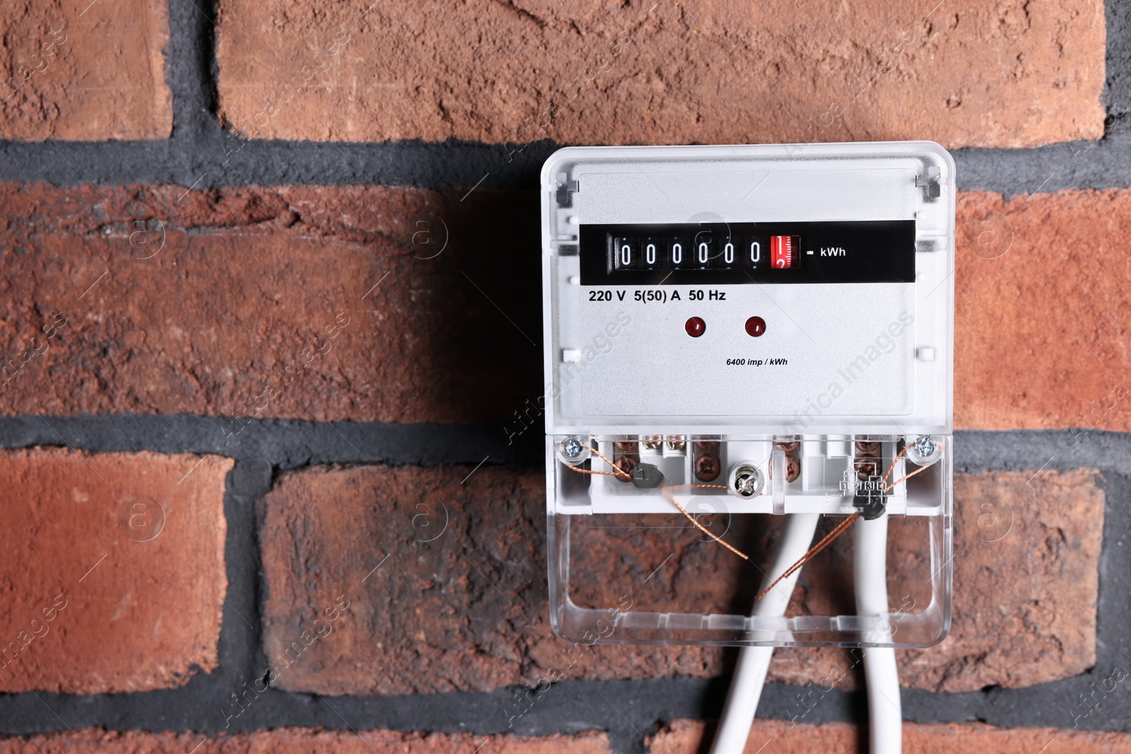 Photo of Electric meter on red brick wall, space for text. Energy measuring device