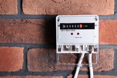 Photo of Electric meter on red brick wall, space for text. Energy measuring device