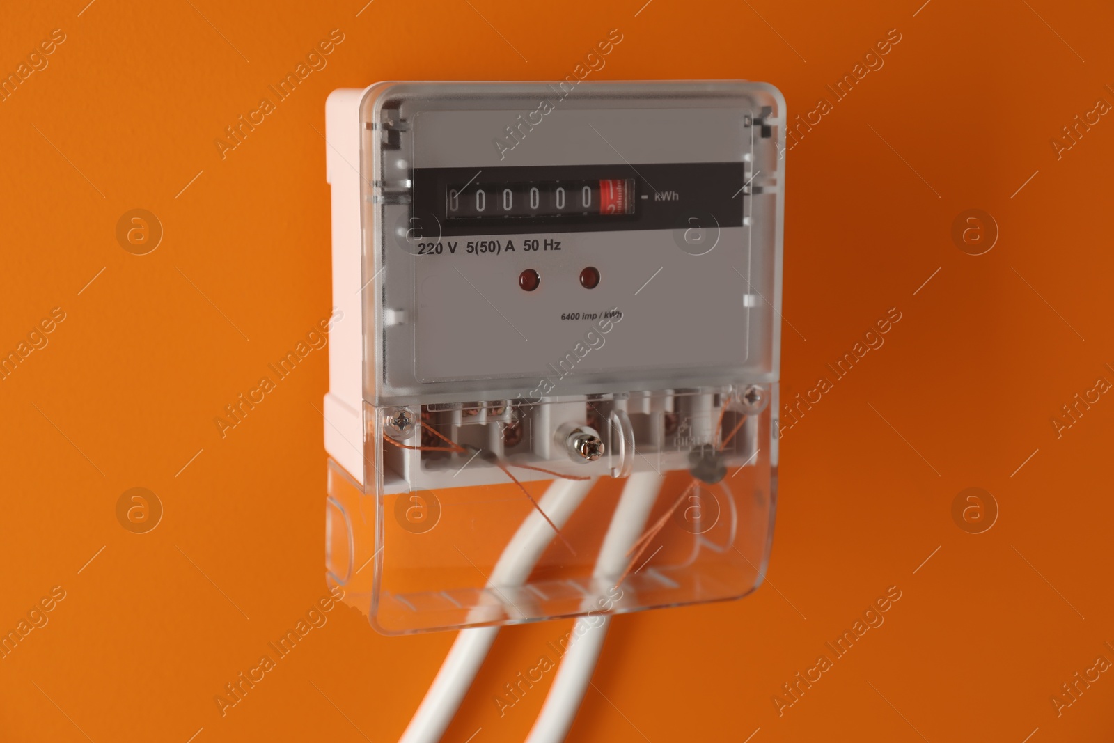 Photo of Electric meter on orange background. Energy measuring device