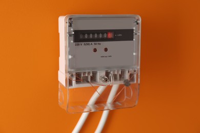 Photo of Electric meter on orange background. Energy measuring device