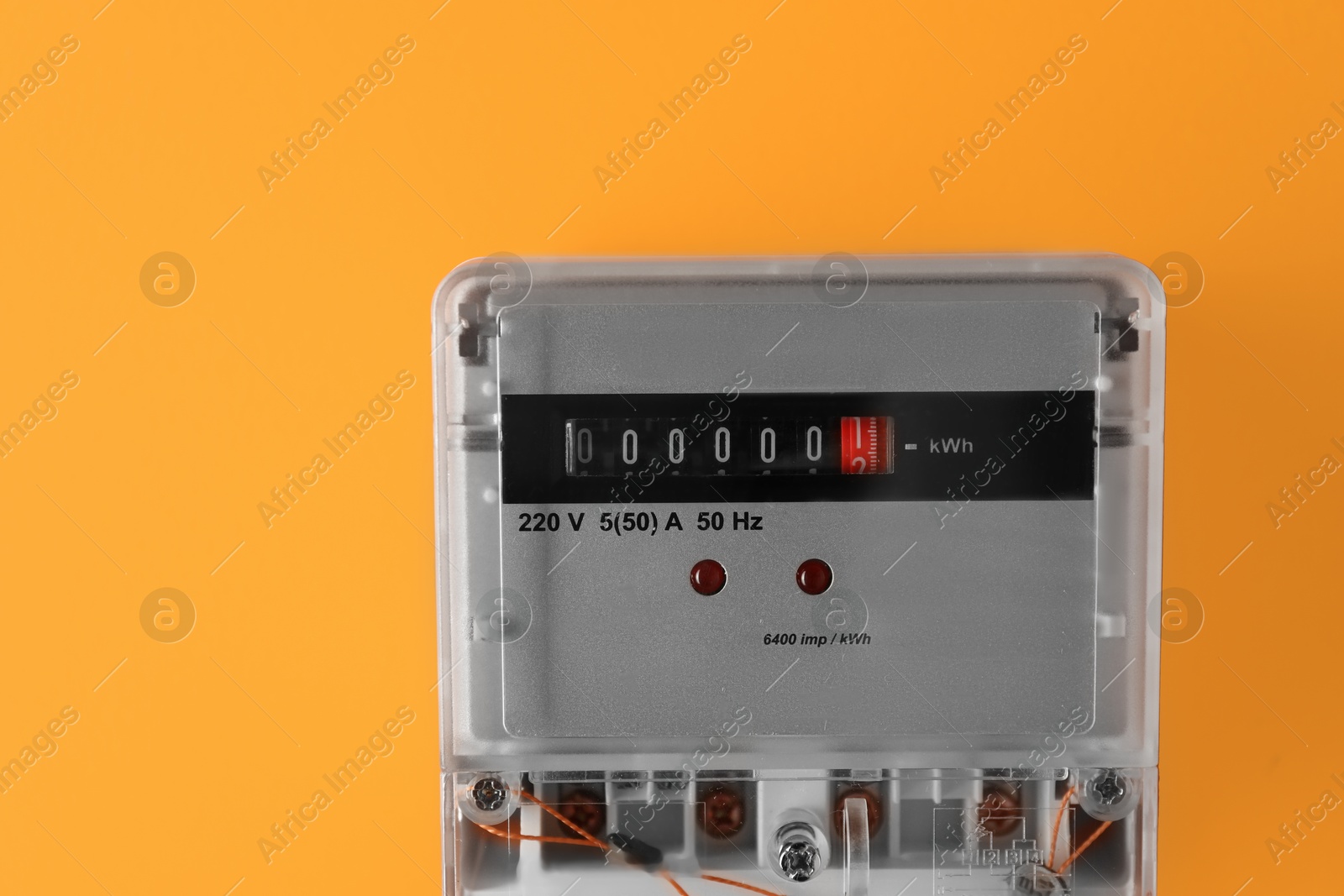 Photo of Electric meter on orange background. Energy measuring device