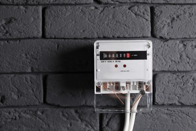 Photo of Electric meter on grey brick wall, space for text. Energy measuring device