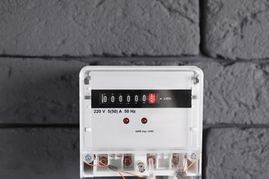 Photo of Electric meter on grey brick wall. Energy measuring device