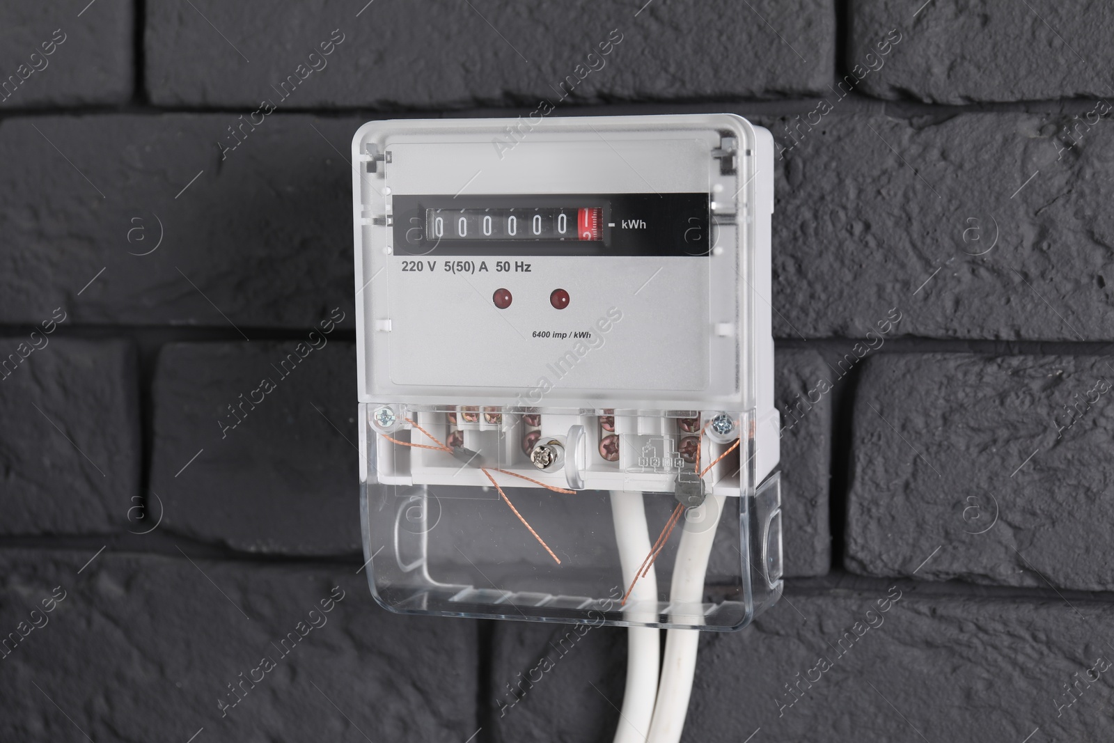 Photo of Electric meter on grey brick wall. Energy measuring device