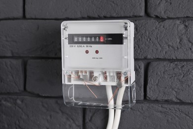 Electric meter on grey brick wall. Energy measuring device