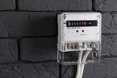 Photo of Electric meter on grey brick wall, space for text. Energy measuring device