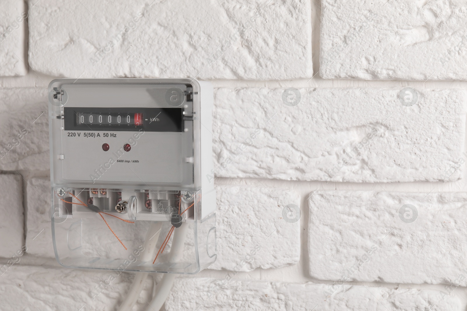 Photo of Electric meter on white brick wall, space for text. Energy measuring device