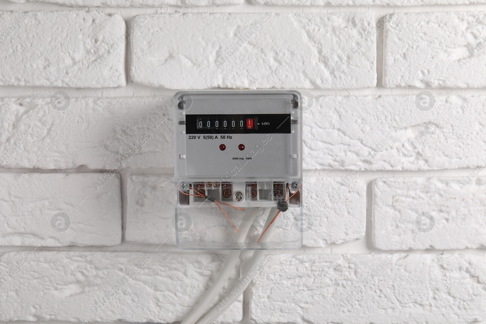 Photo of Electric meter on white brick wall. Energy measuring device