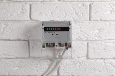 Photo of Electric meter on white brick wall. Energy measuring device