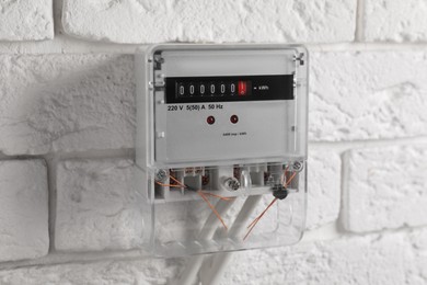 Photo of Electric meter on white brick wall. Energy measuring device