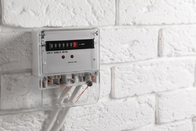 Photo of Electric meter on white brick wall, space for text. Energy measuring device
