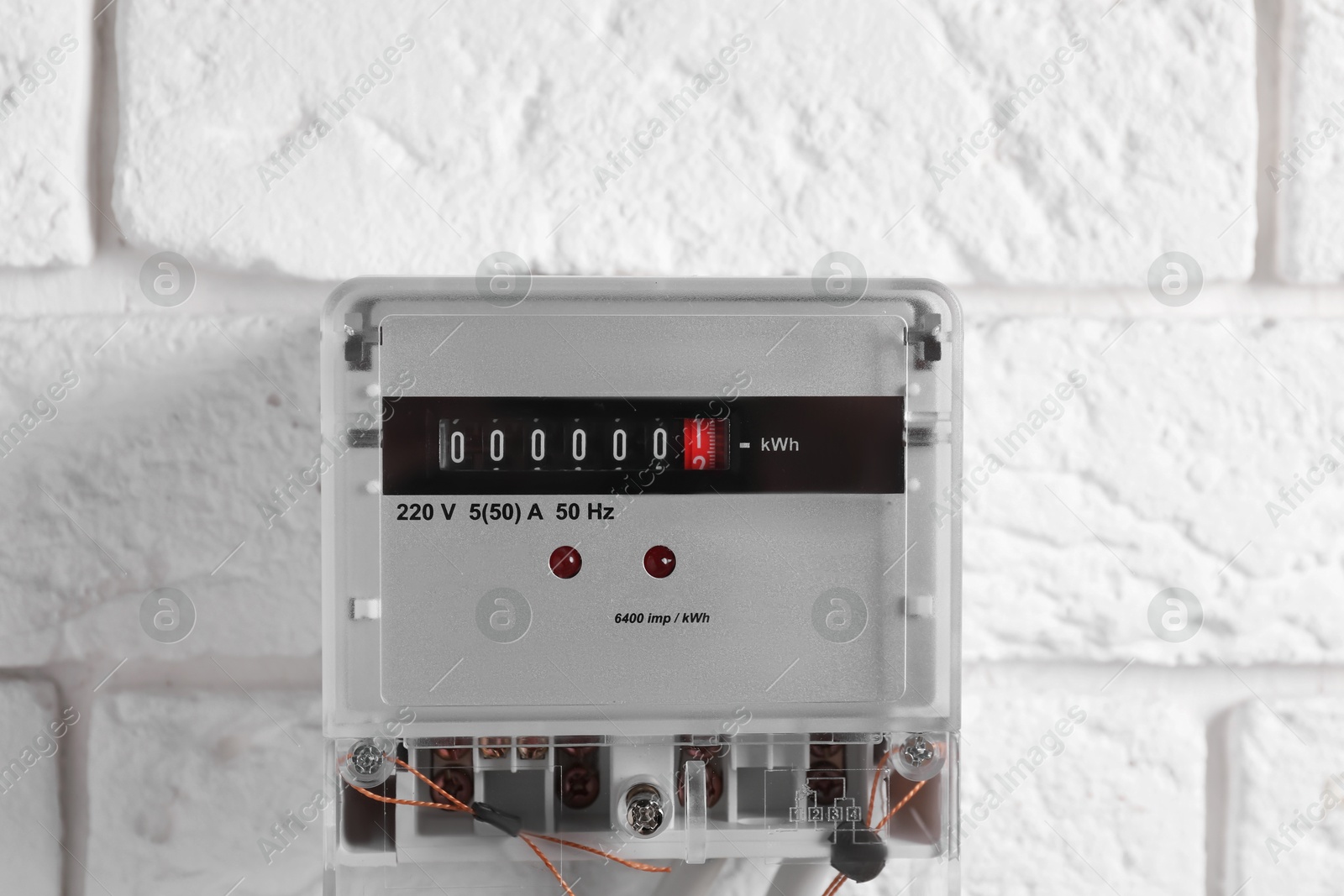 Photo of Electric meter on white brick wall. Energy measuring device