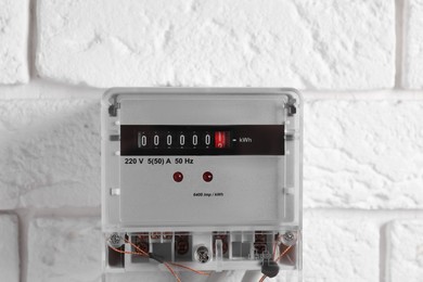 Electric meter on white brick wall. Energy measuring device