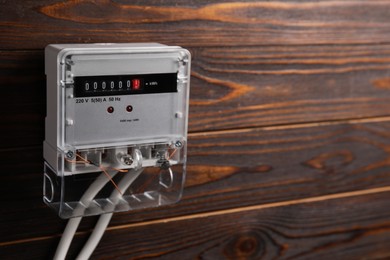Photo of Electric meter on wooden wall, space for text. Energy measuring device