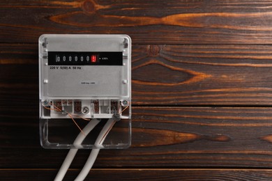 Photo of Electric meter on wooden wall, space for text. Energy measuring device