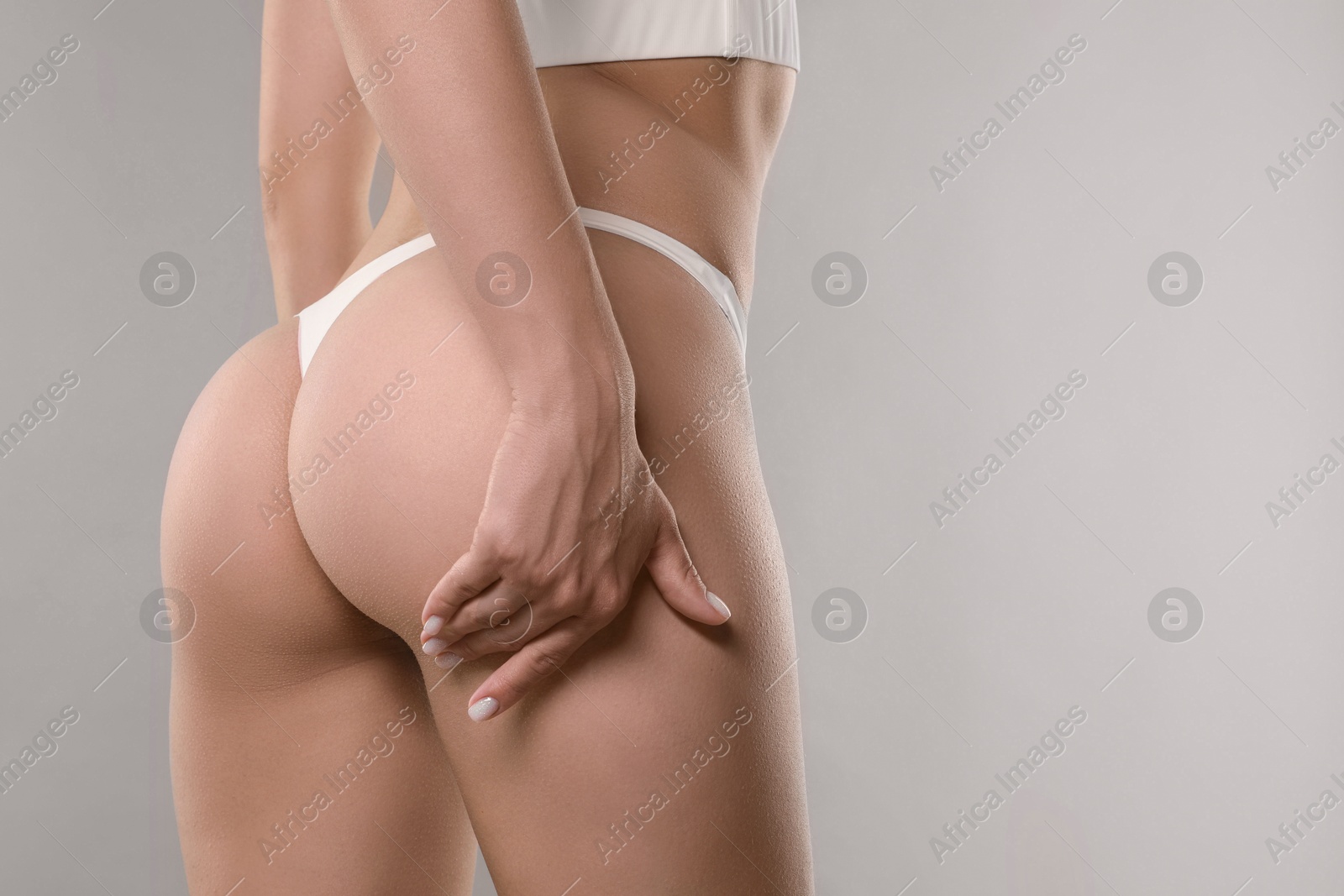 Photo of Woman in underwear on light grey background, closeup. Cellulite problem