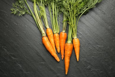 Photo of Tasty ripe juicy carrots on dark gray textured table, top view