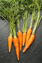 Photo of Tasty ripe juicy carrots on dark gray textured table, top view