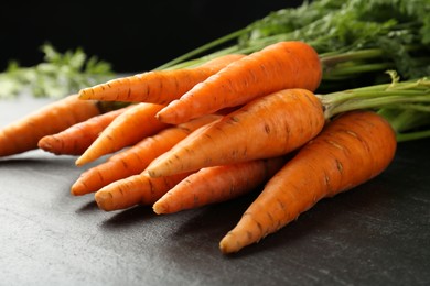 Tasty ripe juicy carrots on dark gray textured table, closeup