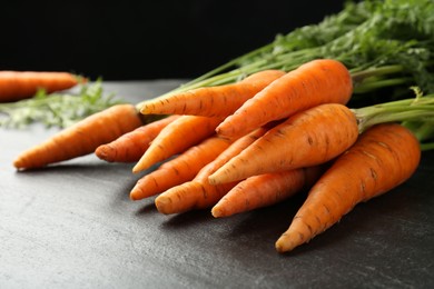 Tasty ripe juicy carrots on dark gray textured table, closeup