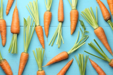 Tasty ripe juicy carrots on light blue wooden table, top view