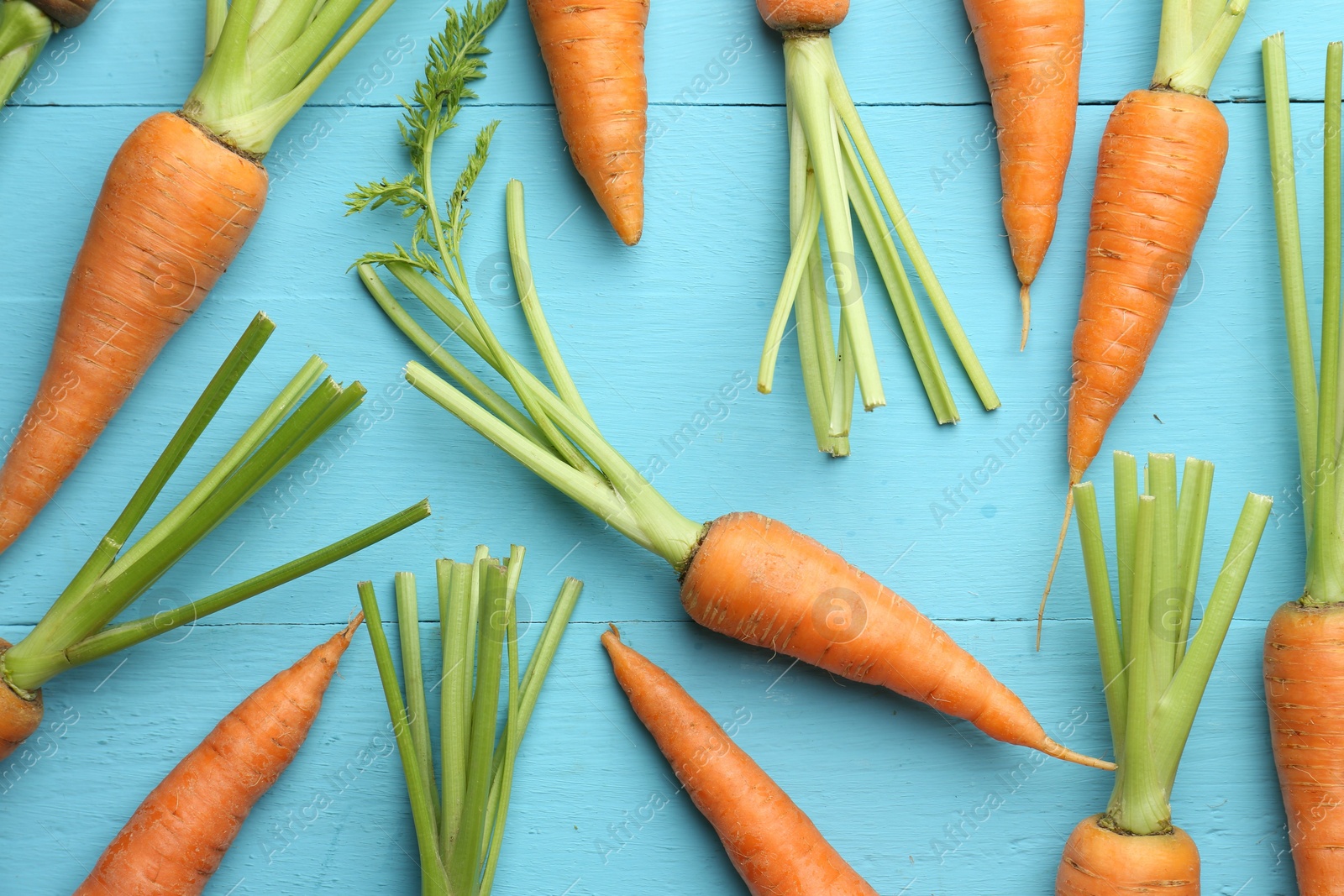 Photo of Tasty ripe juicy carrots on light blue wooden table, top view