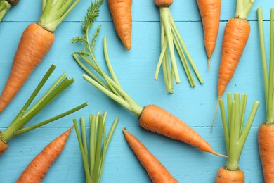 Photo of Tasty ripe juicy carrots on light blue wooden table, top view