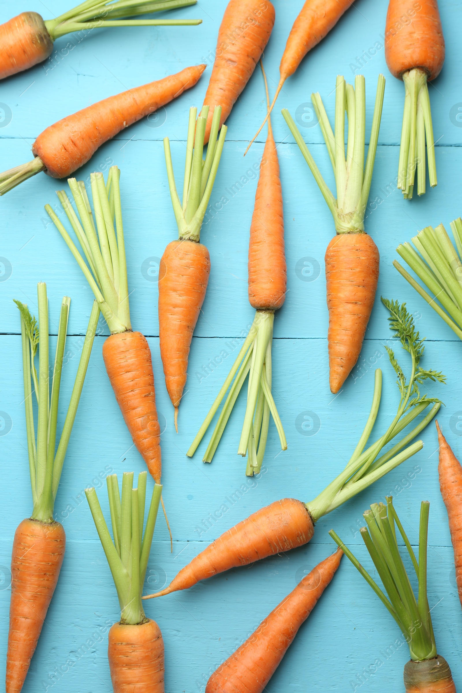 Photo of Tasty ripe juicy carrots on light blue wooden table, top view